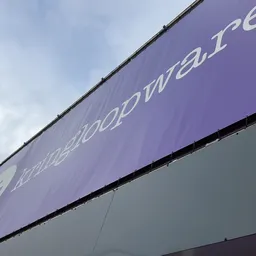 Paarse gevel van kringloopwarenhuis met witte tekst en logo