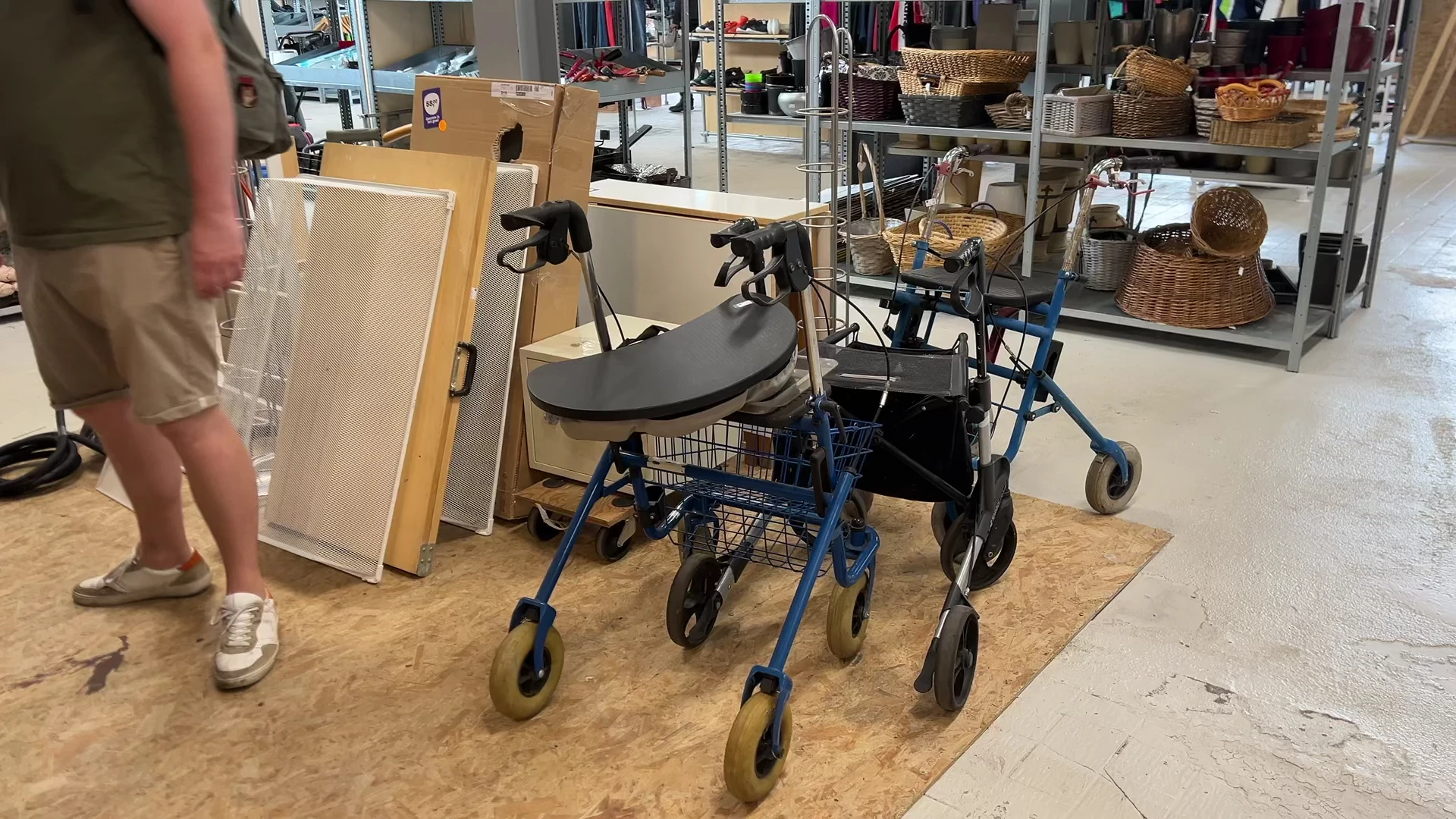 Blauwe rollator met zwart zitje en winkelmandje, op een kurken ondergrond in de winkel