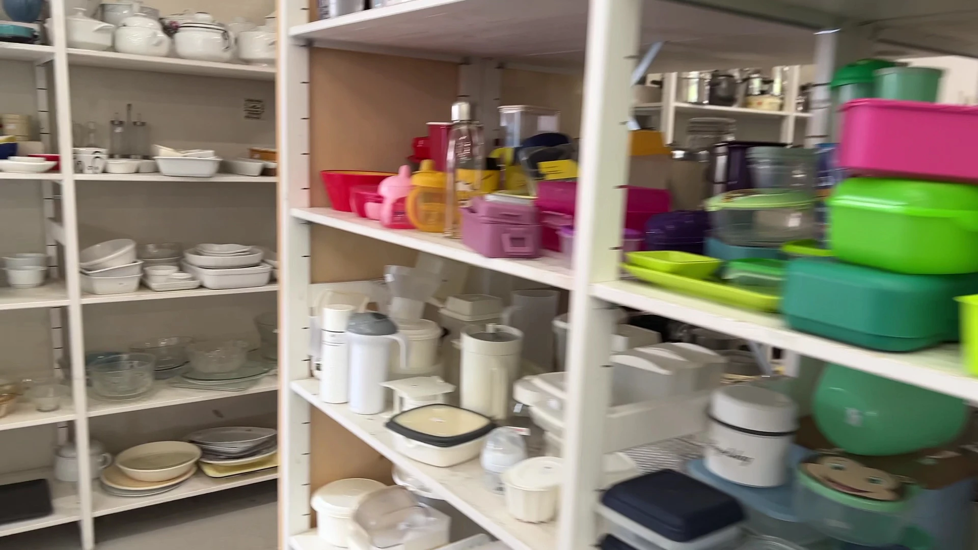 Kastplanken met huishoudartikelen: servies, bakjes, bewaardozen en keukengerei in verschillende kleuren
