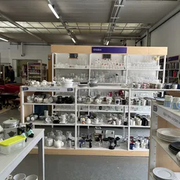 Grote vitrinekast vol met serviesgoed, glazen, kannen en huishoudelijke artikelen netjes uitgestald op meerdere schappen