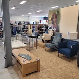 Winkelinterieur met zithoeken, tafels en kledingrekken in de achtergrond