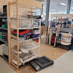 Winkelinterieur met stellingkasten, opbergtassen en diversen huishoudgoederen op de winkelvloer