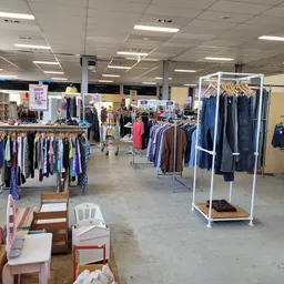 Winkelvloer van kringloopwinkel met rekken vol tweedehands kleding, meubels en huishoudartikelen