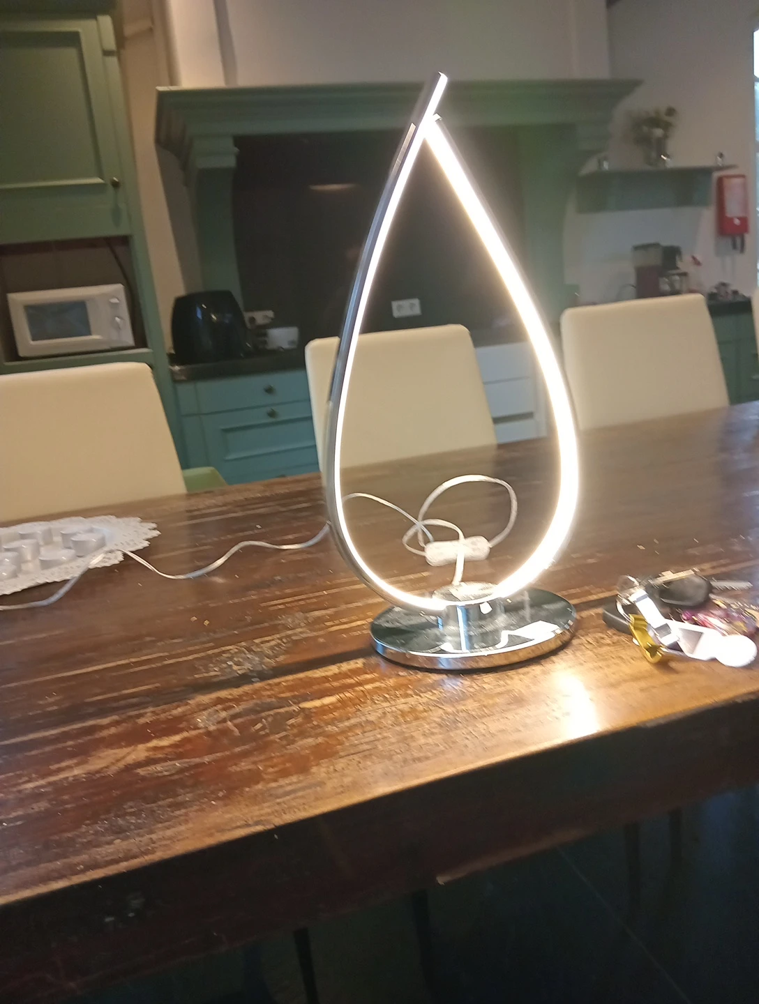 Moderne LED-tafellamp met teardrop-vorm en wit metalen voet op houten tafel