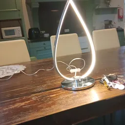 Moderne LED-tafellamp met teardrop-vorm en wit metalen voet op houten tafel