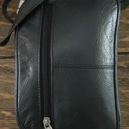 Zwarte lederen clutch of kleine handtas met ritssluiting, op houten ondergrond
