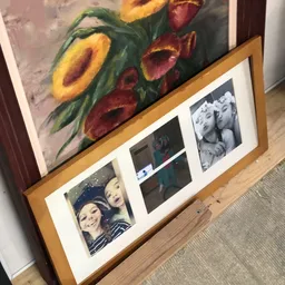 Wanddecoratie met schilderij van bloemen en fotolijst met zwart-witfoto's op houten frame