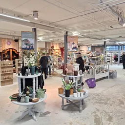 Ruim winkelinterieur met diverse afdeling, displaytafels met huishoudartikelen, klanten aan het winkelen, goed verlicht