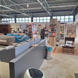 Winkelvloer van kringloopwinkel met toonbank, blauwe meubels, boekenkasten en diverse spullen