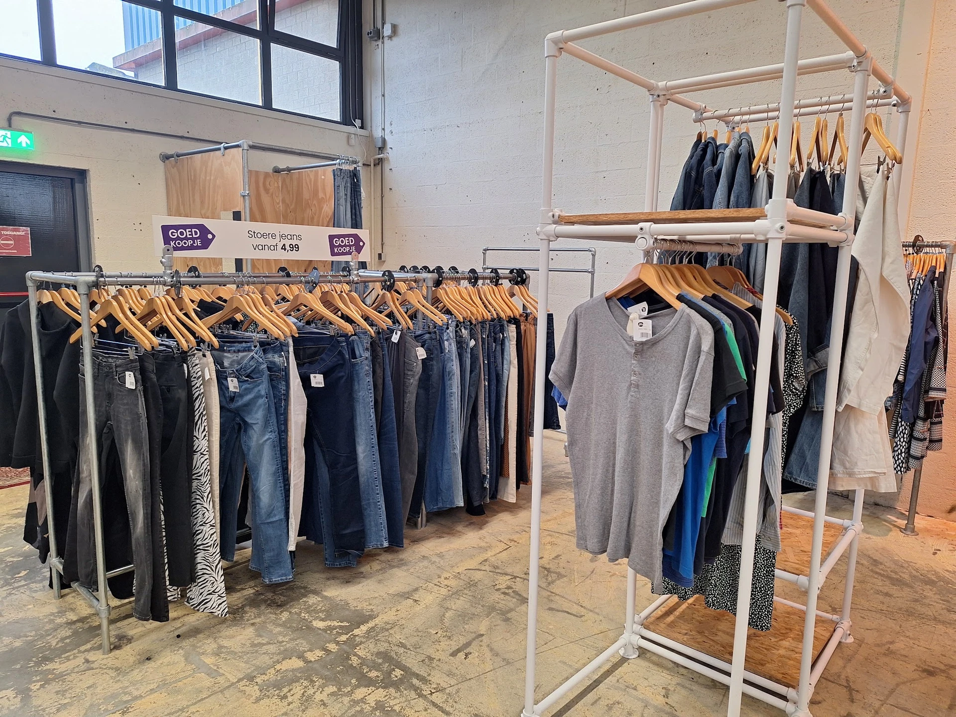 Rekken met tweedehands kleding: jeans, broeken en shirts uitgestald in de winkel