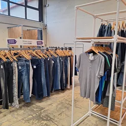 Rekken met tweedehands kleding: jeans, broeken en shirts uitgestald in de winkel