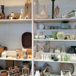 Witte stellingen vol huishoudelijke artikelen, decoratie en serviesgoed in de winkel