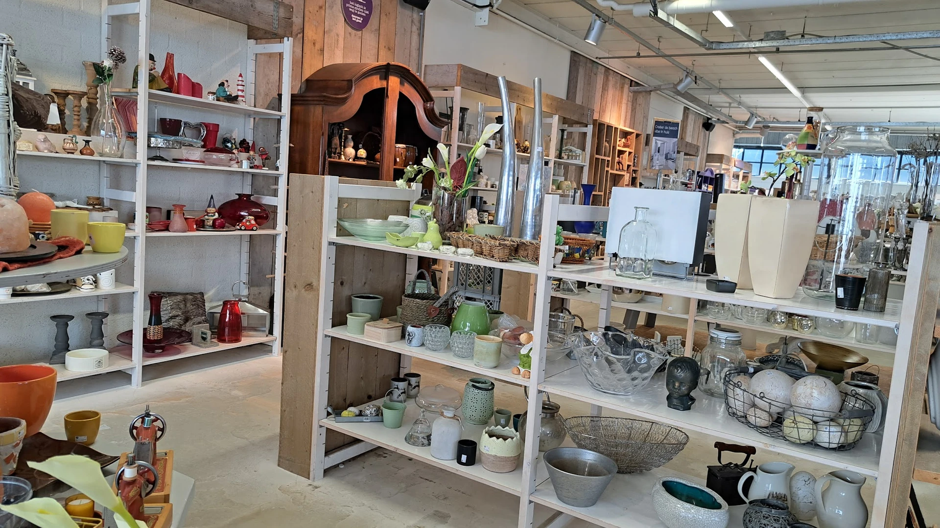 Stellingen met huishoudelijke artikelen, servies, decoratie en keramische items in een kringloopwinkel