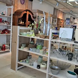 Stellingen met huishoudelijke artikelen, servies, decoratie en keramische items in een kringloopwinkel