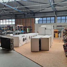 Wasmachines en droogkasten in een rij in de winkelhal van een kringloopwinkel