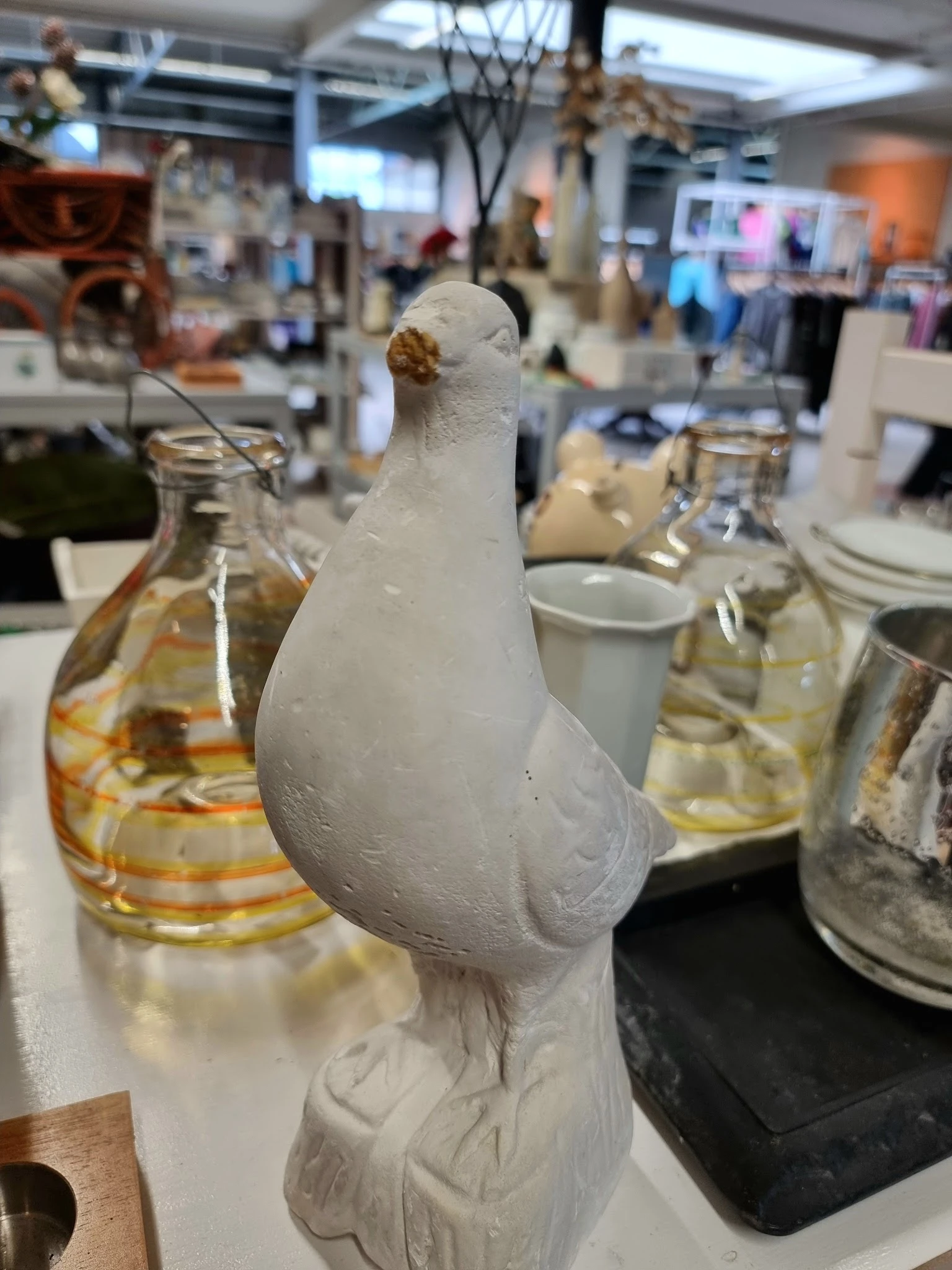 Witte decoratieve vogel met gouden detail op tafel met glazen op achtergrond