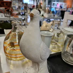 Witte decoratieve vogel met gouden detail op tafel met glazen op achtergrond