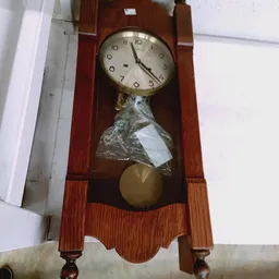 Houten wandklok met slingerwerk en koperen slinger, nog in verpakking
