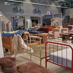 Winkelvloer met meubels: bedden met metalen frames, stoelen, kasten en andere tweede­hands meublair