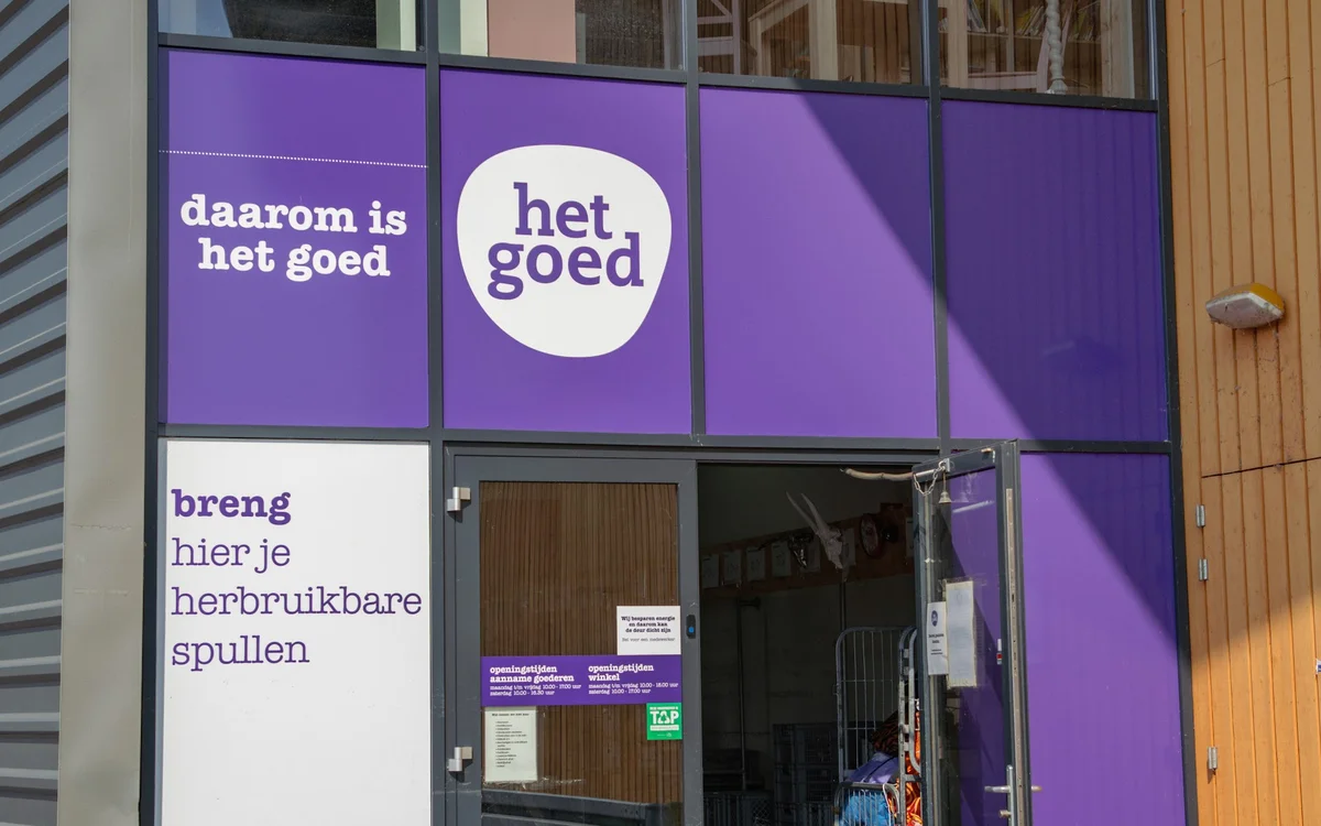 Paarse winkelpui met witte raamstickers met tekst 'daarom is het goed' en 'het goed', winkelname leesbaar