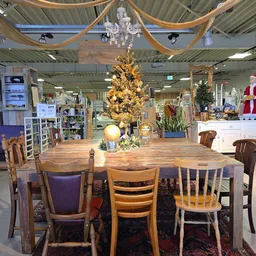 Winkelinterieur met houten eettafel, stoelen en gouden kerstboom als decoratie