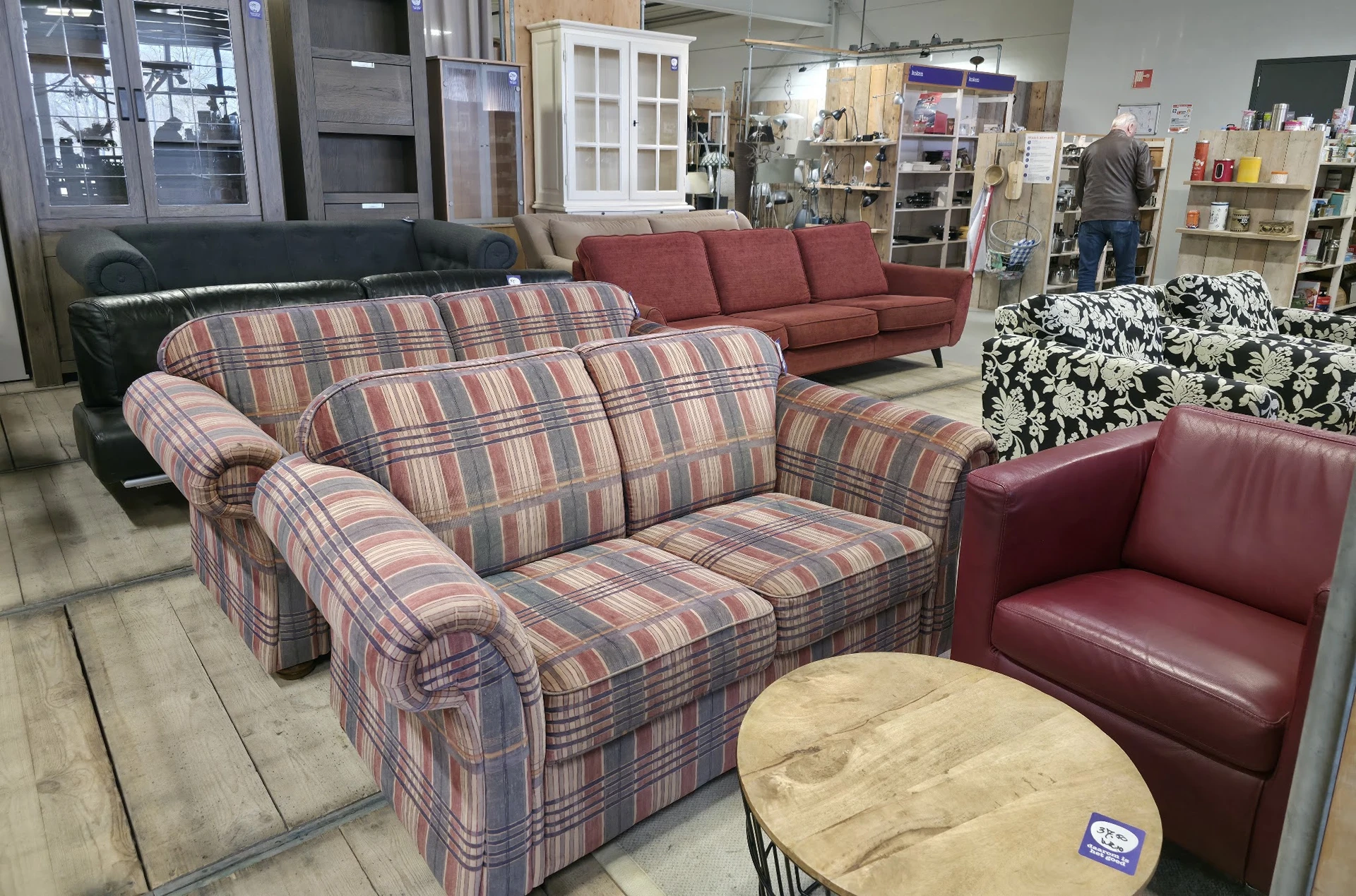 Uitgestalde meubels in de kringloopwinkel, waaronder gestreepte stoelen en rode banken
