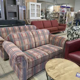 Uitgestalde meubels in de kringloopwinkel, waaronder gestreepte stoelen en rode banken