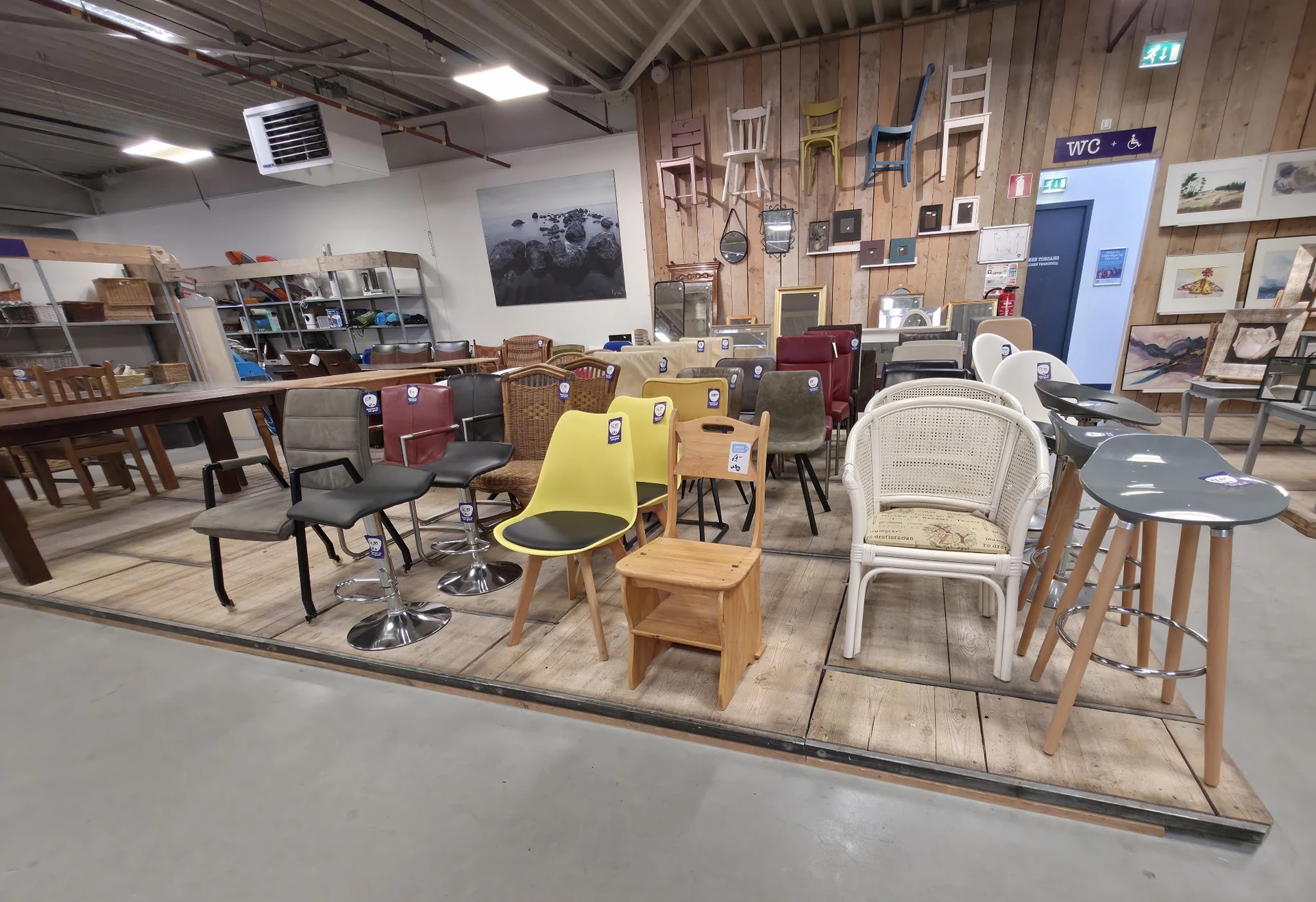 Winkelvloer met diverse meubels en inrichting, waaronder stoelen, tafels en kasten op uitgestalde oppervlakte