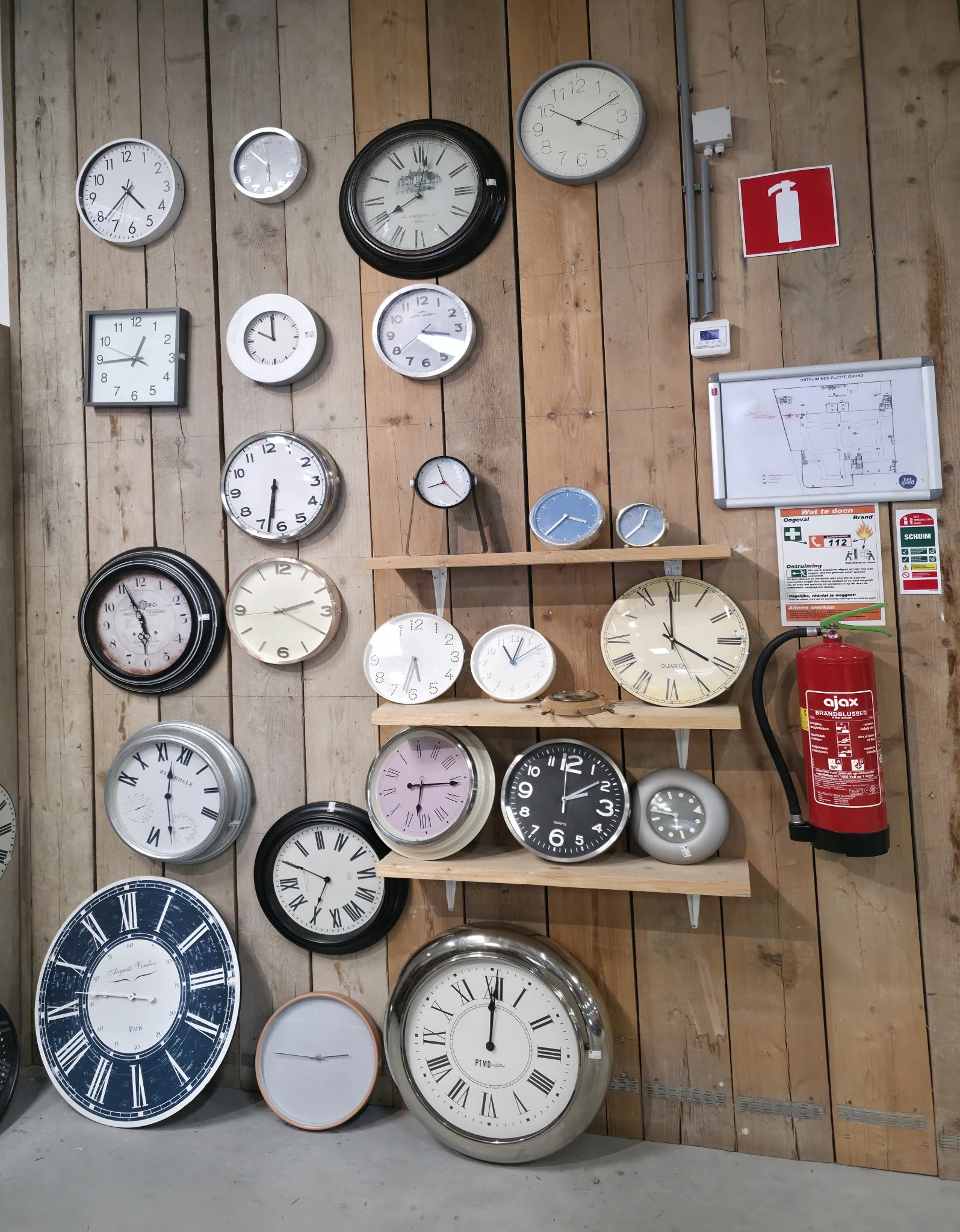 Verzameling van diverse wandklokken en klokken op houten wanden en planken, met verschillende stijlen en maten