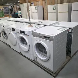 Rij met witte wasmachines en droogkasten uitgestald in een kringloopwinkel