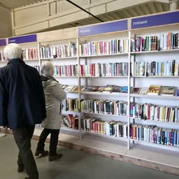 Bezoekers bekijken boekenrekken met boeken in een kringloopwinkel