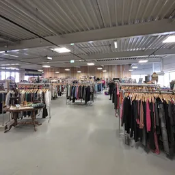 Winkelvloer met rekken vol tweedehands kleding, goed verlicht met moderne plafondverlichting
