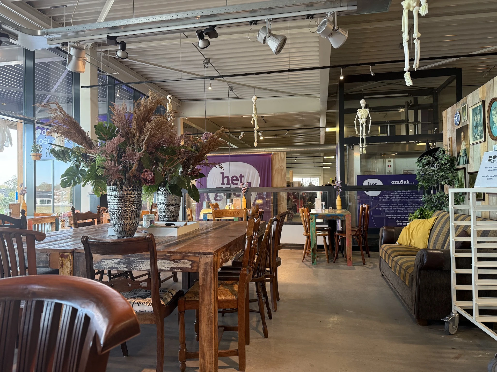 Ruime winkelruimte met houten eettafel, stoelen, decoratie en verlichtingsarmaturen hangend aan het plafond