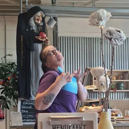 Vrijwilliger in paarse shirt demonstreert keramische of aardewerk item in de winkel