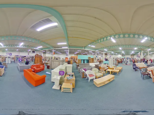 Ruime winkelhal met turquoise golvend plafond, gevuld met diverse tweedehands meubels en spullen