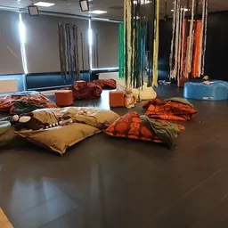 Zitzakken en poefs in diverse kleuren op donkere vloer in winkelruimte met stellingen op achtergrond