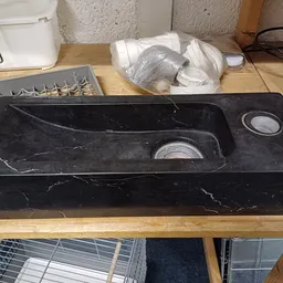 Zwarte marmeren wastafel met twee ronde spoelbakken op houten werkblad