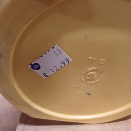 Geel/crèmekleurig serviesgoed met prijskaartje €12,99 in een schaal