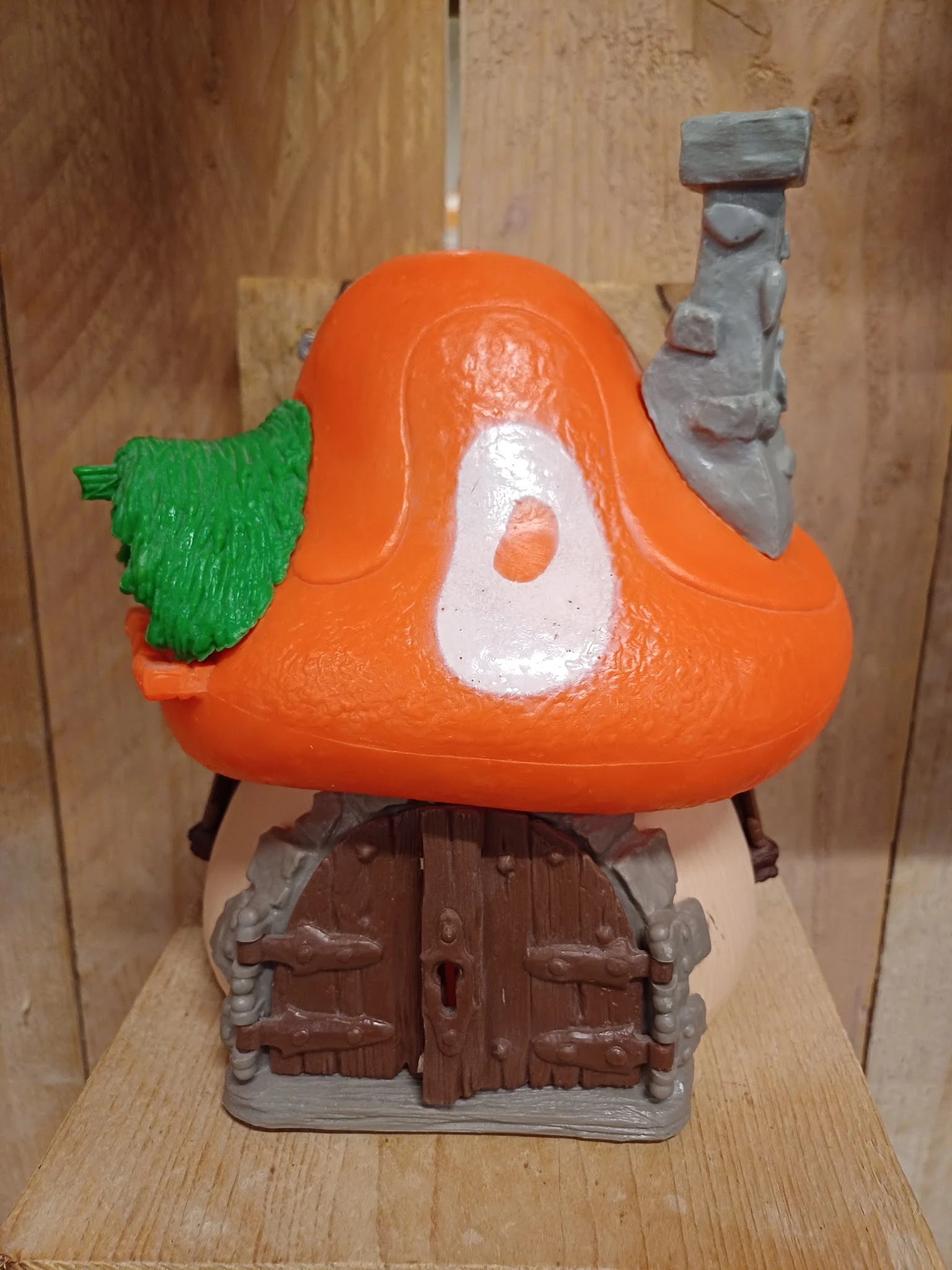 Close-up van een oranje speelgoedfiguur met groen blad en wit detail op de borst