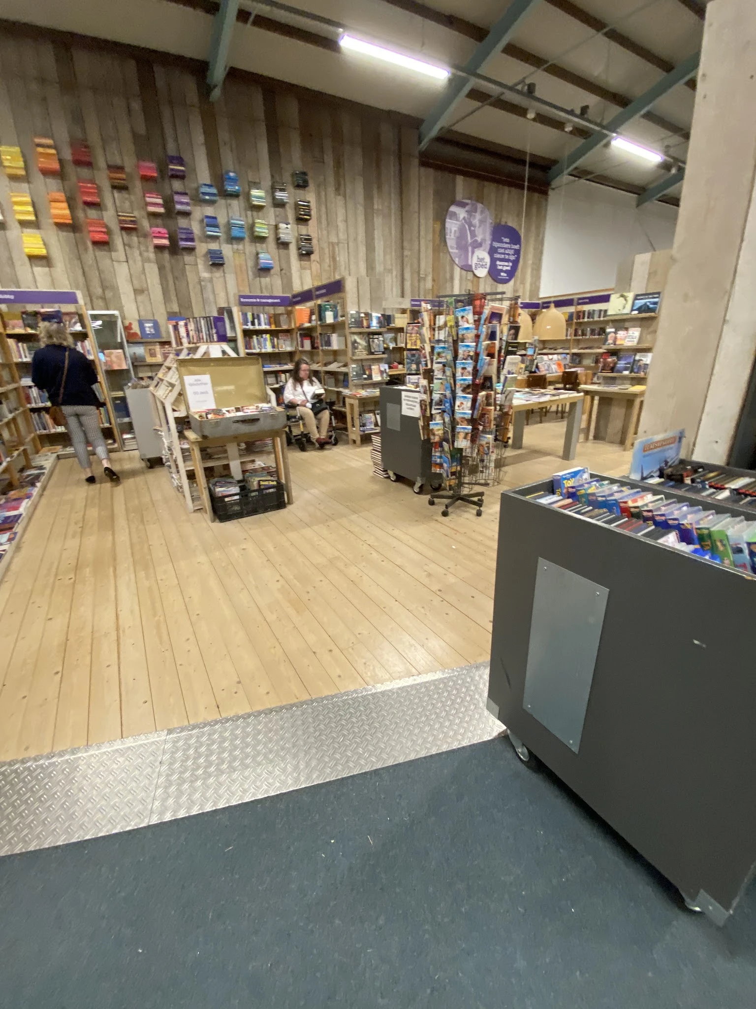 Winkelvloer van kringloopwinkel met houten planken, boekenrekken, displaytafels en winkelkasten vol tweedehands artikelen