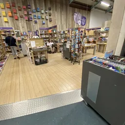 Winkelvloer van kringloopwinkel met houten planken, boekenrekken, displaytafels en winkelkasten vol tweedehands artikelen