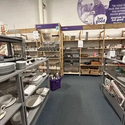 Winkelvloer van kringloopwinkel met stellingen vol servies, huishoudartikelen en diverse spullen