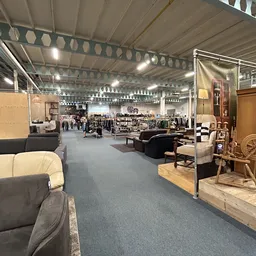 Ruim winkelinterieur met meubels, kleding en huisraad op stellingen en display