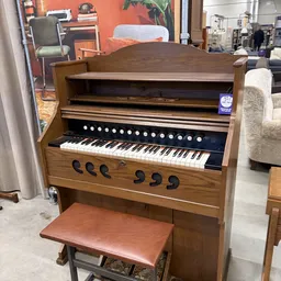 Houten elektronisch orgel met zwart toetsenbord en witte toetsen, op showroom