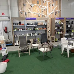 Winkelinterieur met stellingen vol huishoudartikelen, stoelen en meubels op groene vloer