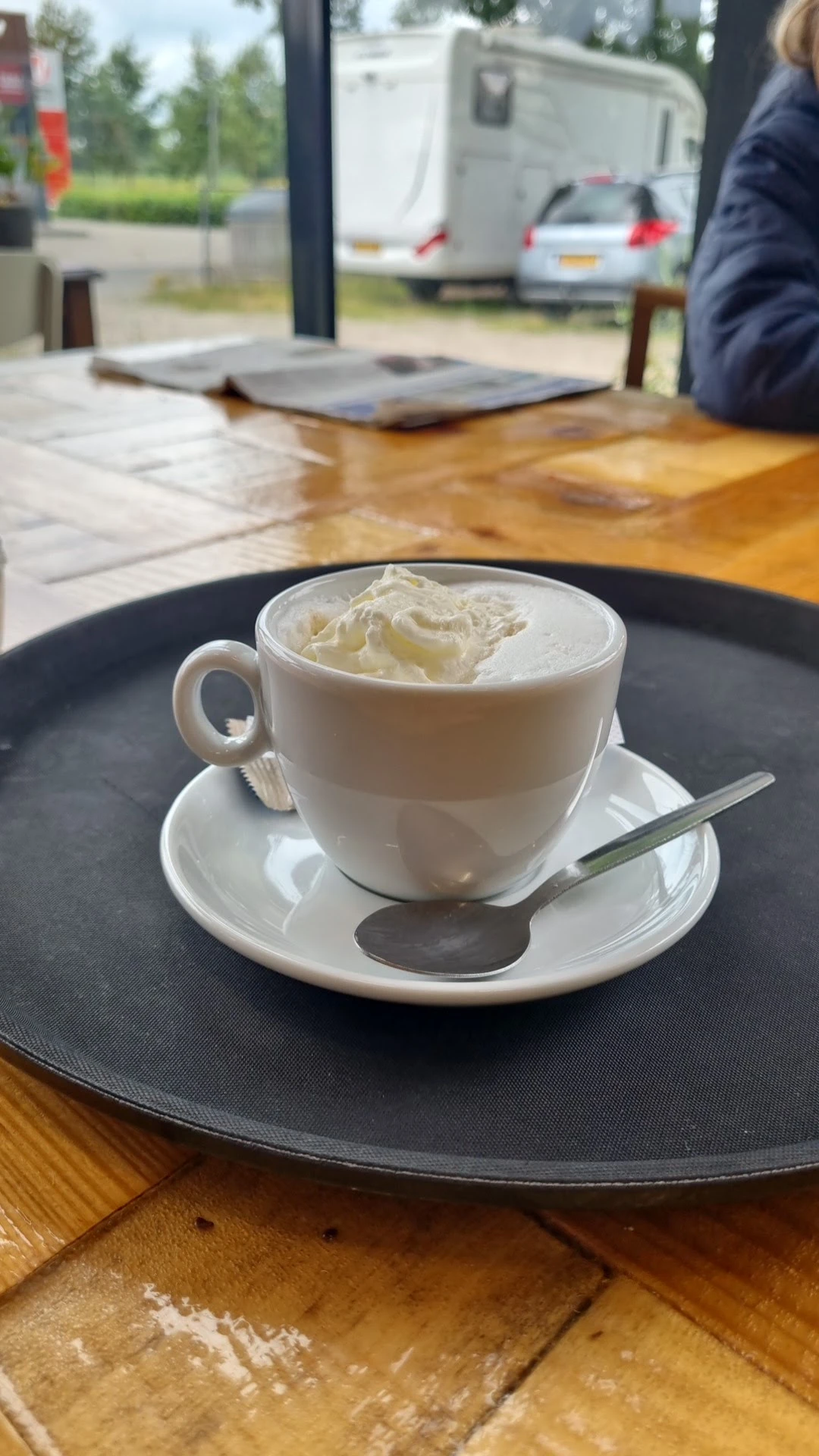 Kopje koffie met slagroom op schotel met lepel in lunchroom