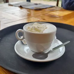 Kopje koffie met slagroom op schotel met lepel in lunchroom