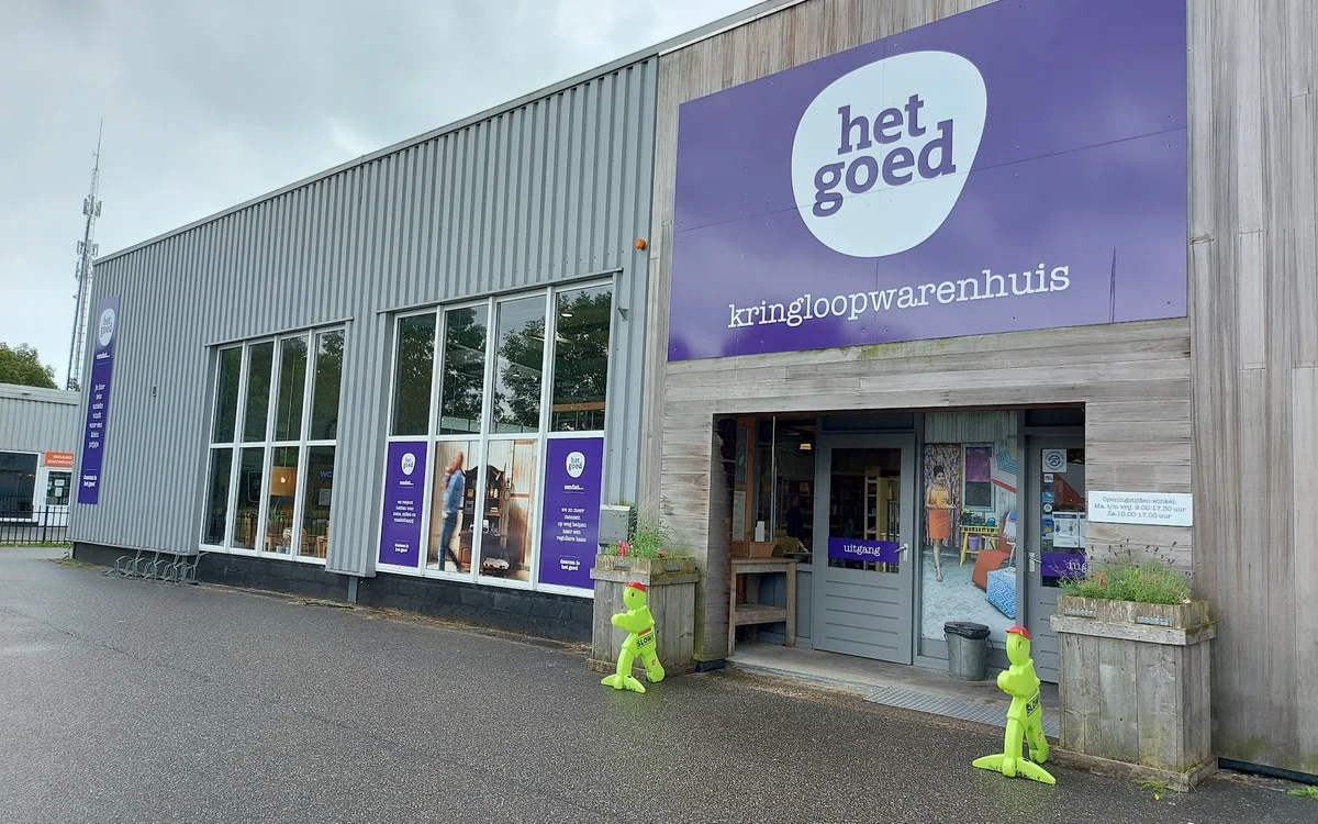 Gevel van kringloopwinkel Het Goed met paars logo en 'kringloopwarenhuis' tekst, moderne houten constructie met grote ramen
