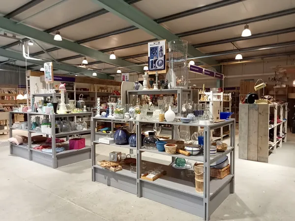 Winkelvloer met meerdere vitrinekastjes vol huishoudelijke artikelen en decoratie onder halogeenverlichting