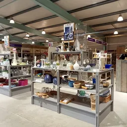 Winkelvloer met meerdere vitrinekastjes vol huishoudelijke artikelen en decoratie onder halogeenverlichting